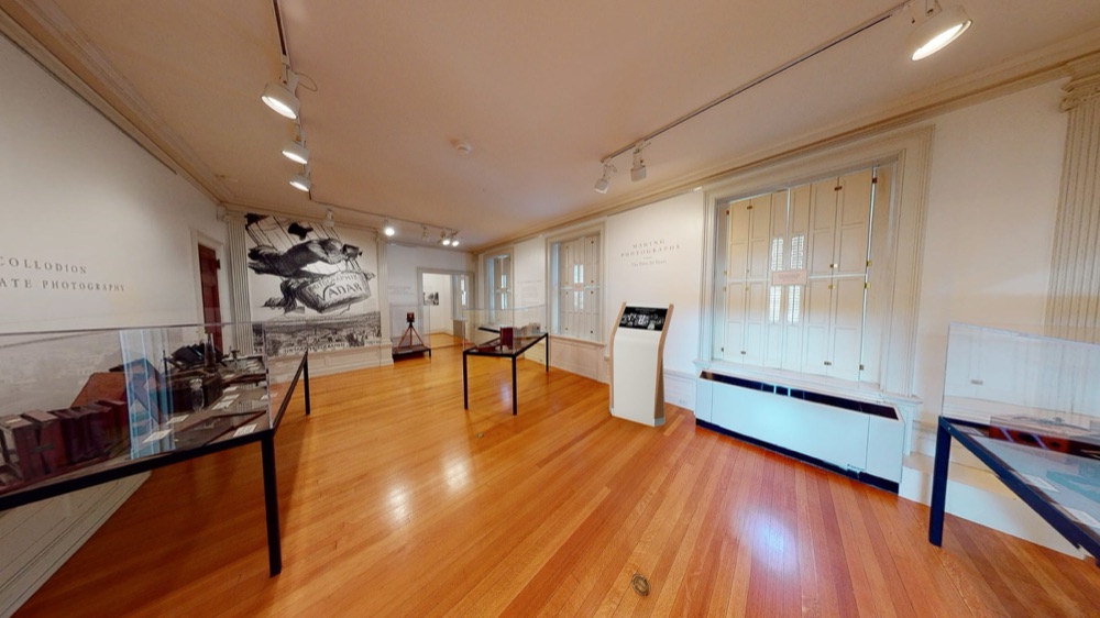 Wide view of a museum gallery with the Kodak timeline kiosk standing by the windows